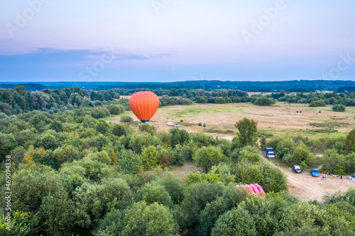 Summer landscape at the mouth of the Klyazma river in the Vladimir region. An orange balloon prepares for takeoff. Sunset in the Russian field