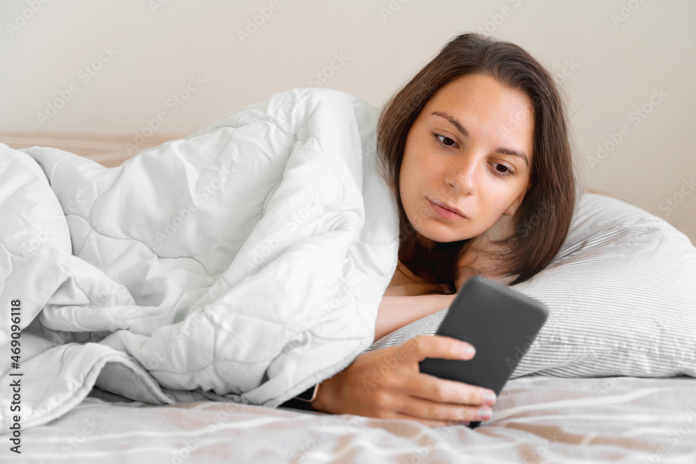 Young woman goes to sleep Phone addiction, insomnia. try to fall asleep. Sleep tracking on the phone. Circadian rhythm. Young woman goes to sleep Phone addiction, insomnia. try to fall asleep. Sleep tracking on the phone. Circadian rhythm.