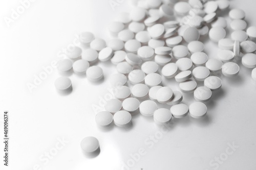 scattered white pills on white reflective background