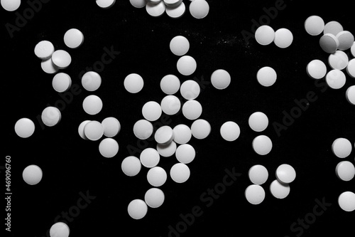 scattered white pills on black background