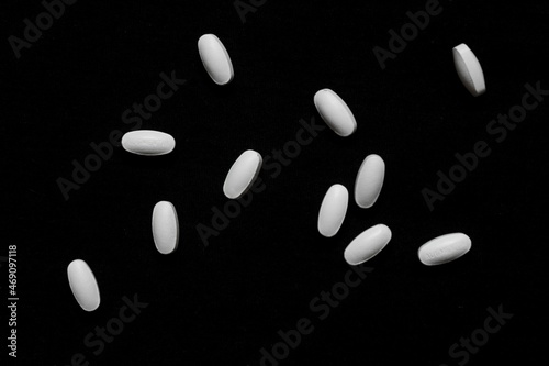 scattered white pills on black background