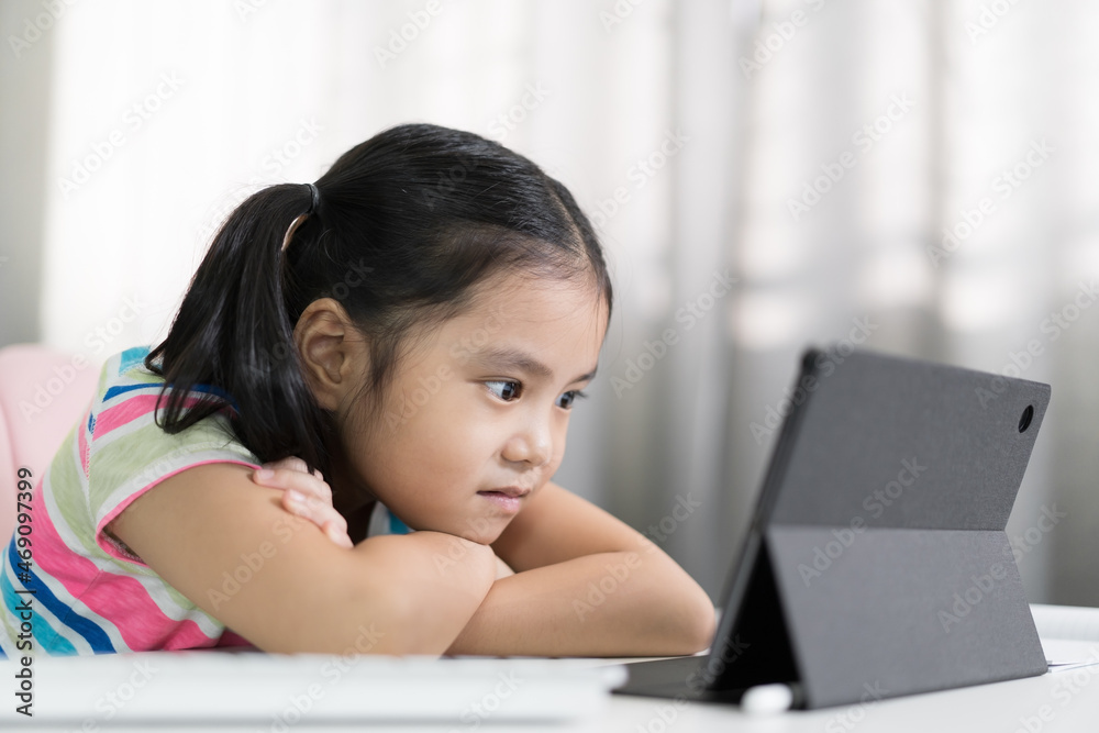 asian child smile lying on table to studying online on tablet or kid girl student back to school by video call learning class and read looking on computer or person learn from home on pad in classroom asian child smile lying on table to studying online on tablet or kid girl student back to school by video call learning class and read looking on computer or person learn from home on pad in classroom