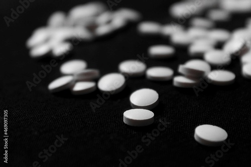 scattered white pills on black background