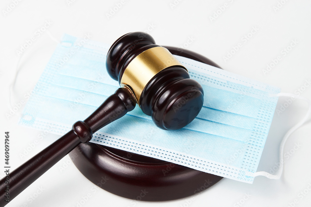 Judge gavel and medical protective mask on a white background