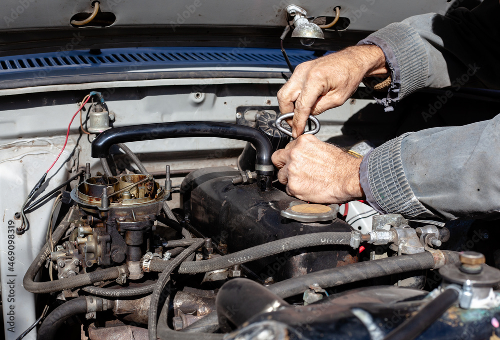 the mechanic uses a screwdriver to disassemble old engine. DIY repair. troubleshooting process. under the hood working the mechanic uses a screwdriver to disassemble old engine. DIY repair. troubleshooting process. under the hood working