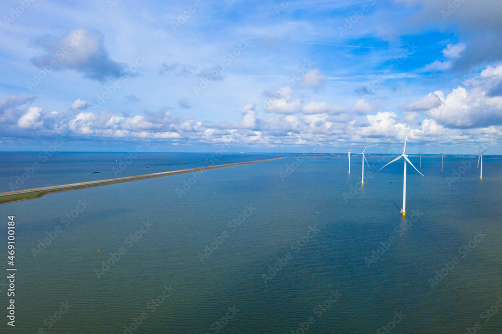 Fototapeta premium Drone photography of enormous windmills stand in the sea along a dutch sea. Fryslân wind farm, the largest inland wind farm in the world. Friesland, Afsluitdiijk, Ijsselmeer, Breezanddijk, Netherlands