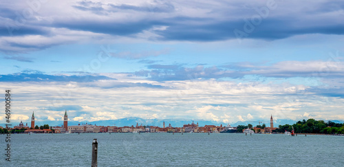 Scenic view of beautiful sea water surface with wooden post along with city buildings in the background