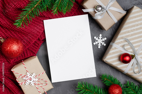 Christmas or New Year greeting card mockup with decorated gift boxes and fir tree branches on red knitted background