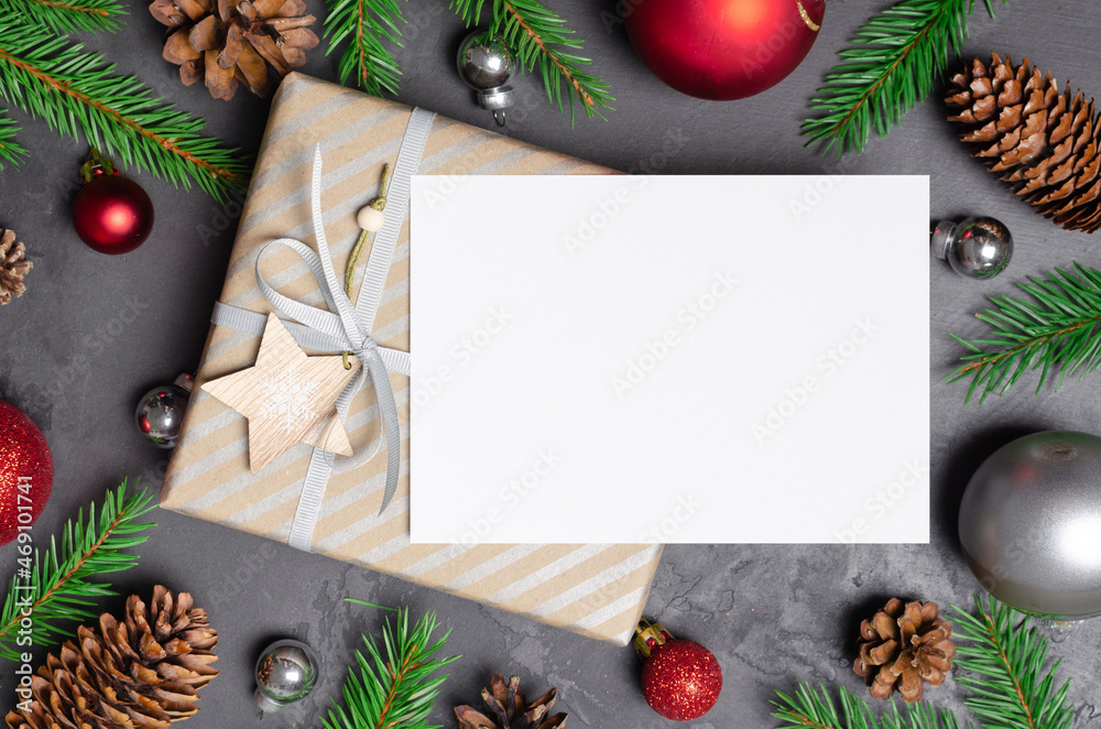 Christmas greeting card mockup with gift, festive decorations, fir tree twigs and cones on dark background Christmas greeting card mockup with gift, festive decorations, fir tree twigs and cones on dark background