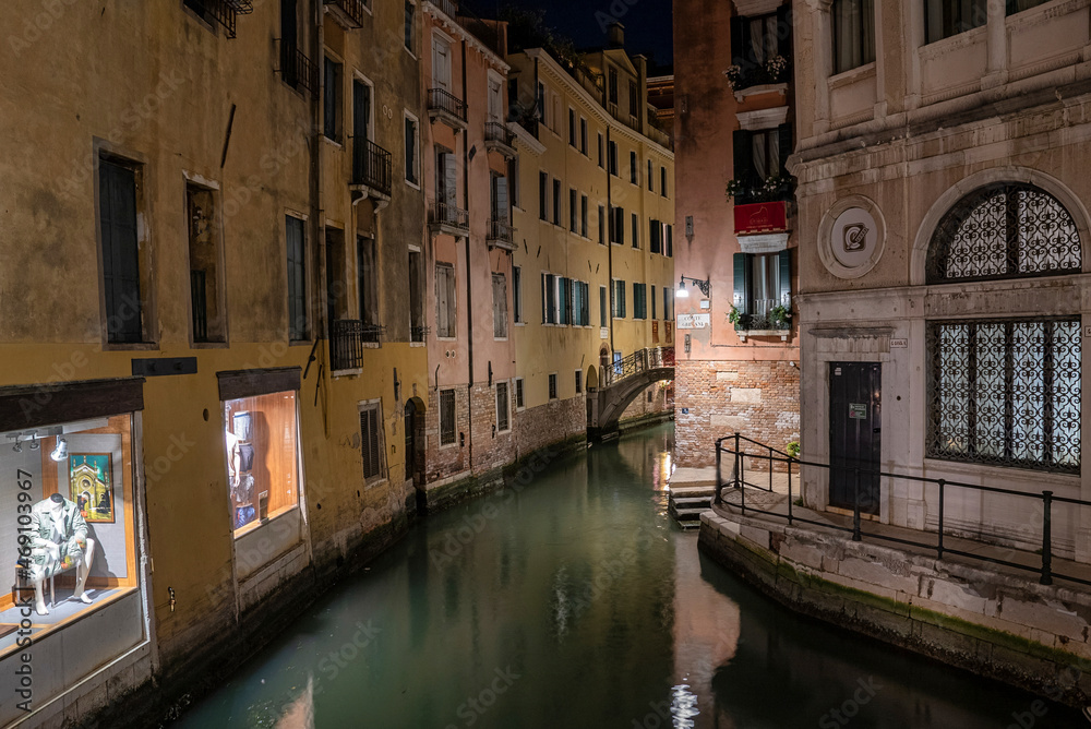 Narrow canal between historic residential building illuminated with lamps at night