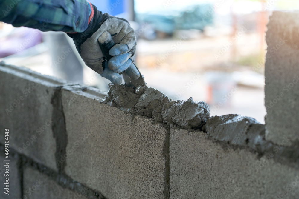 © ปราณี จิรกิจเดโชกุล - masonry worker make concrete wall by cement block and plaster at construction site