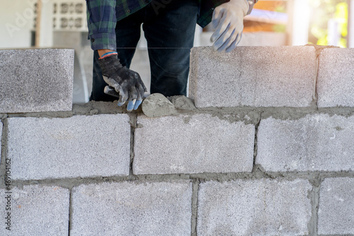 Fotografia masonry worker make concrete wall by cement block and plaster at construction si