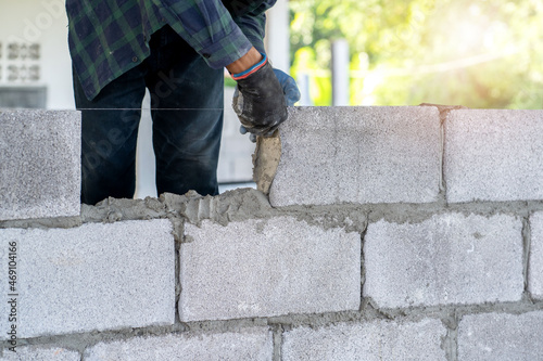 masonry worker make concrete wall by cement block and plaster at construction site