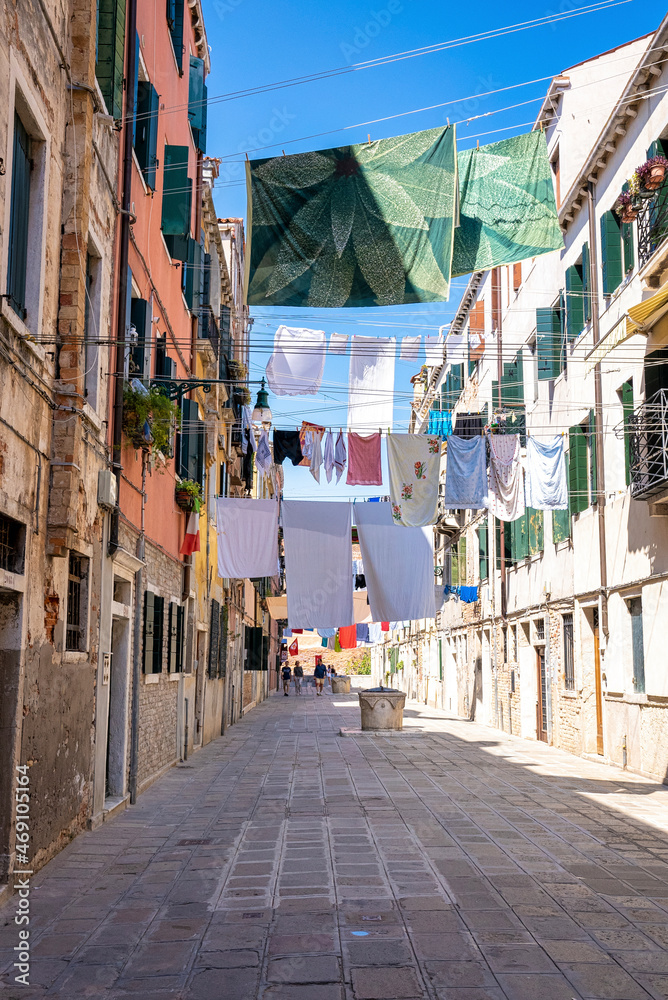 Footpath of a narrow residential building with old houses and clothes hanging for drying on clothesline on a summer day