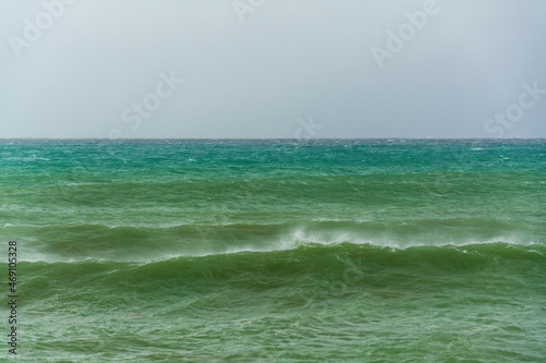 angry turquoise green color massive rip curl of a waves as it barrel rolls along the ocean. wild waves pound the coastline of chabahar in stormy day with cloudy sky close to coastline ,oman sea © AAref