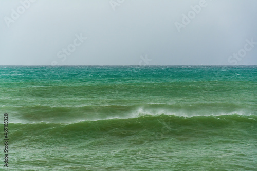 angry turquoise green color massive rip curl of a waves as it barrel rolls along the ocean. wild waves pound the coastline of chabahar in stormy day with cloudy sky close to coastline  oman sea