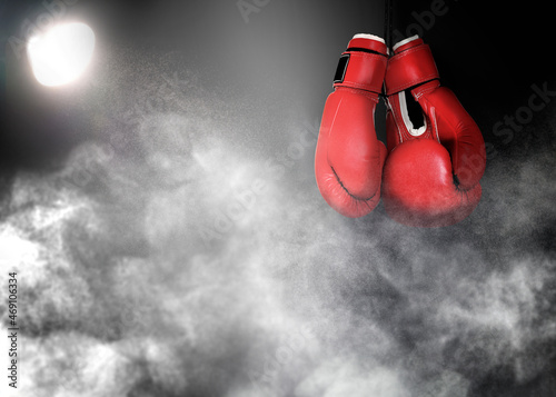Pair of boxing gloves and white smoke illuminated by spotlight on dark background © New Africa