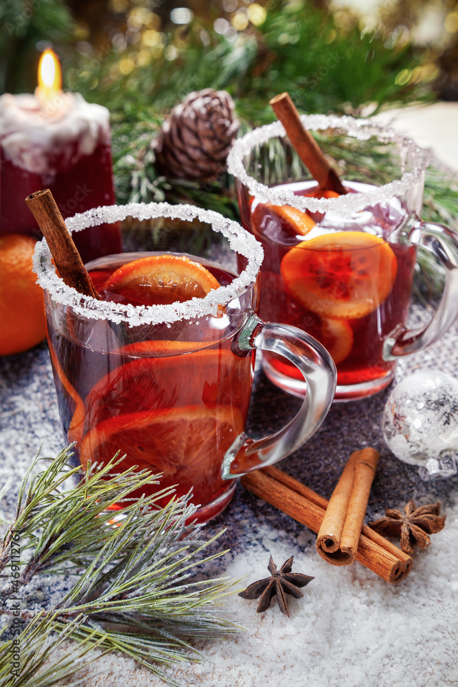 Christmas hot mulled wine with a slice of orange and spices. A glass cup with a hot traditional drink on a snowy background in festive decorations. Evening mood and decoration Christmas hot mulled wine with a slice of orange and spices. A glass cup with a hot traditional drink on a snowy background in festive decorations. Evening mood and decoration