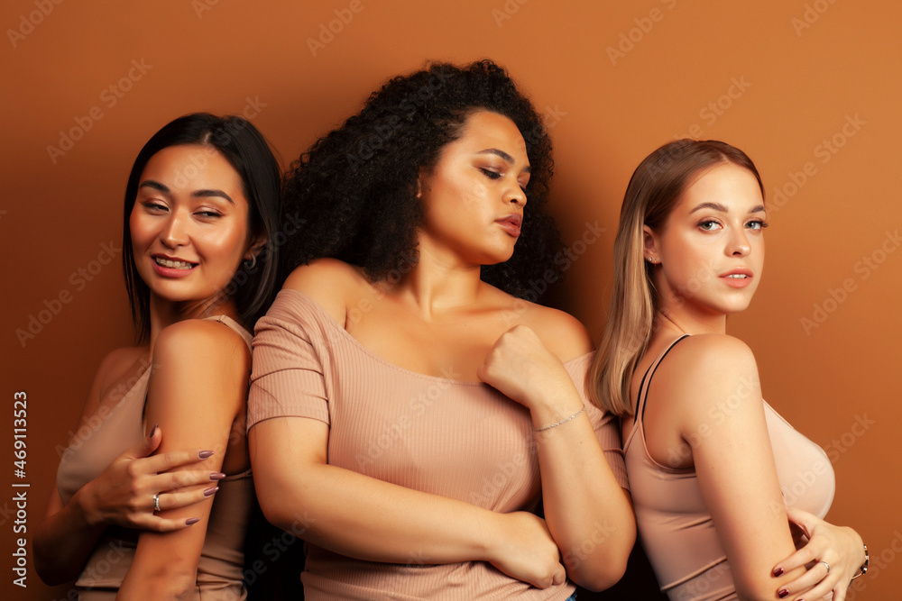 young pretty asian, caucasian, afro woman posing cheerful together on brown background, lifestyle diverse nationality people concept young pretty asian, caucasian, afro woman posing cheerful together on brown background, lifestyle diverse nationality people concept