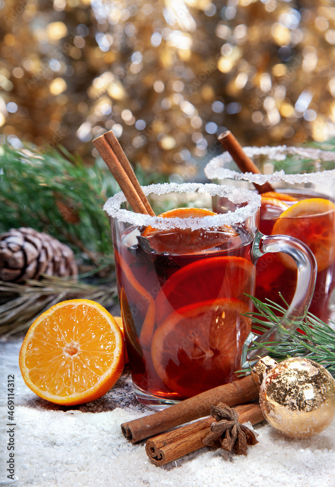 Christmas hot mulled wine with a slice of orange and spices. A glass cup with a hot traditional drink on a snowy background in festive decorations. Evening mood and decoration Christmas hot mulled wine with a slice of orange and spices. A glass cup with a hot traditional drink on a snowy background in festive decorations. Evening mood and decoration