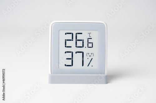 A home weather station standing on a white background is a modern device with a screen showing the temperature and humidity in the room. Front view. studio shot