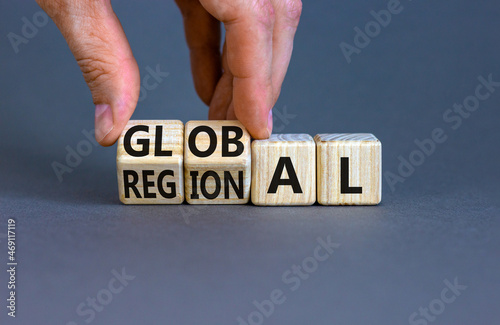 Regional or global symbol. Businessman turns wooden cubes and changes the word 'regional' to 'global'. Beautiful grey table, grey background. Business and regional or global concept. Copy space. photo