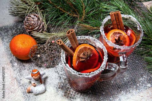 Christmas hot mulled wine with a slice of orange and spices. A glass cup with a hot traditional drink on a snowy background in festive decorations. Evening mood and decoration 