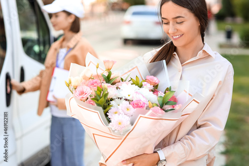 Woman with bouquet of flowers received from courier outdoors