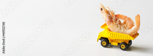 Yellow toy truck carries shrimps. Seafood transportation and delivery concept. The concept of transportation of large oversized cargo. Free space for an inscription. Web banner