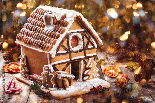 Gingerbread house. Christmas gingerbread house over lights of Christmas decorated fir tree