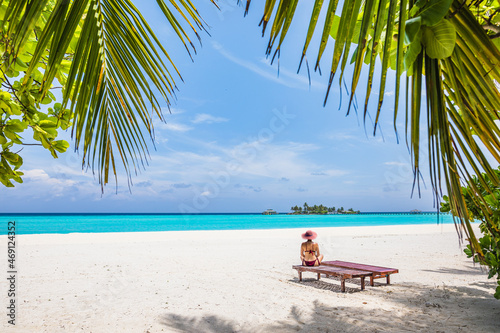 The girl is sitting on a beach lounger on a paradise island with azure water and exotic vegetation