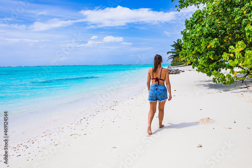 The girl is walking on a paradise island with turquoise water and exotic vegetation - the Maldives