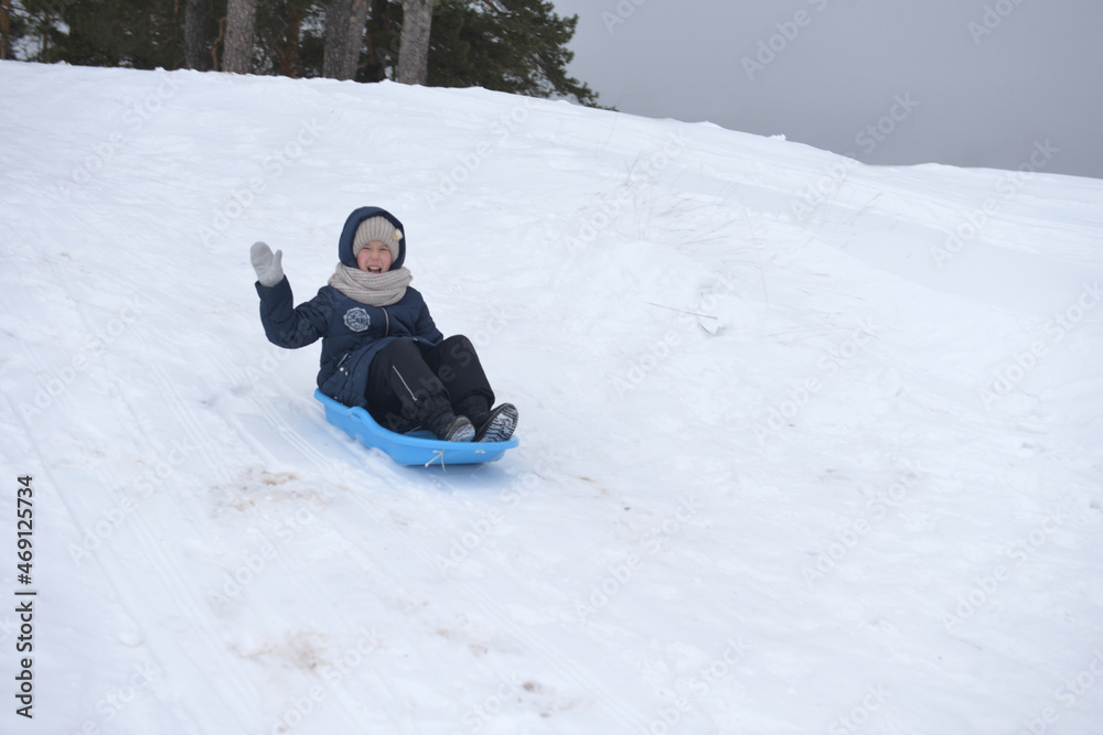 The girl slides down the snow slide and smiles