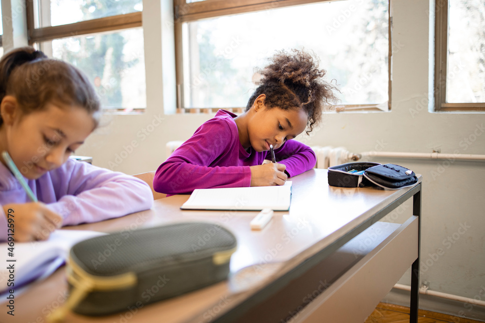 Portrait of an Afro American girl at school doing test in classroom. - obrazy, fototapety, plakaty 
