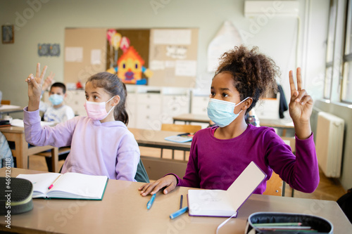 Children with face masks in school classroom during corona virus pandemic.