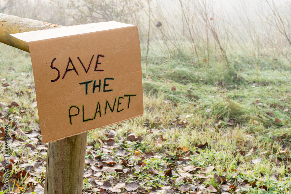 Cardboard sign placed on a wooden railing with the slogan -Save the Planet-