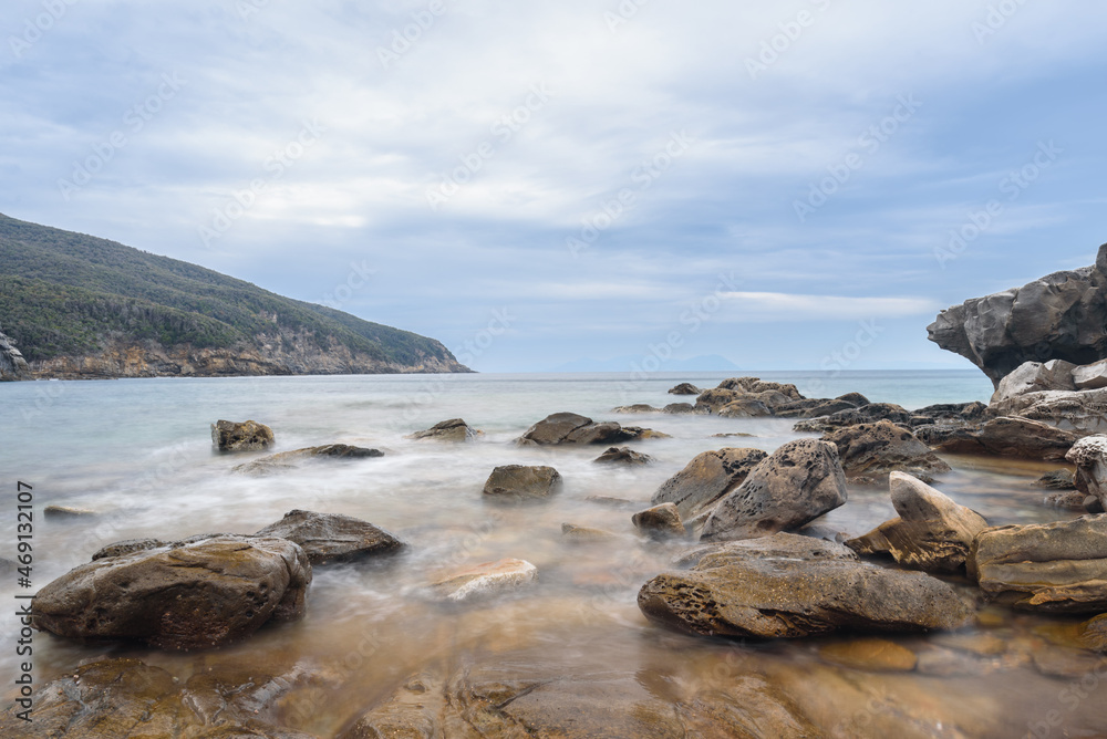 Felsen in der Bucca delle Fate mit Blick Richtung Isola del Elba, Toskana, Italien mit Wolken und Bergen