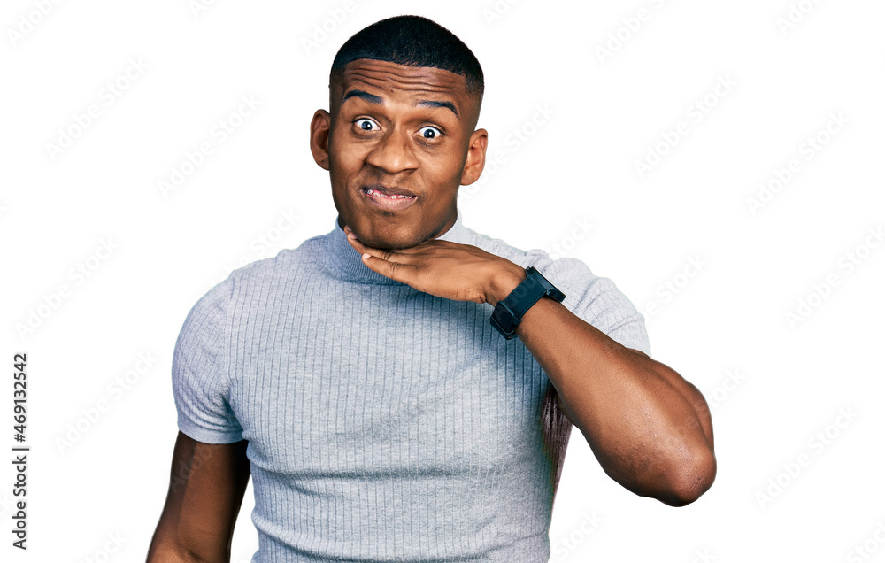Young black man wearing casual t shirt cutting throat with hand as knife, threaten aggression with furious violence Young black man wearing casual t shirt cutting throat with hand as knife, threaten aggression with furious violence