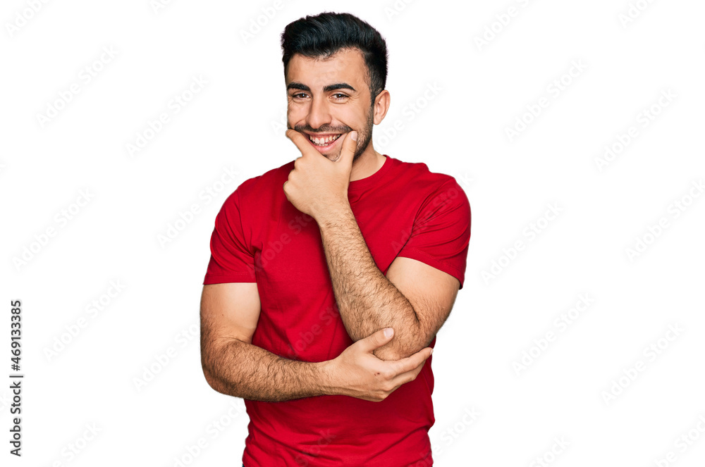 Hispanic man with beard wearing casual red t shirt looking confident at the camera smiling with crossed arms and hand raised on chin. thinking positive. Hispanic man with beard wearing casual red t shirt looking confident at the camera smiling with crossed arms and hand raised on chin. thinking positive.