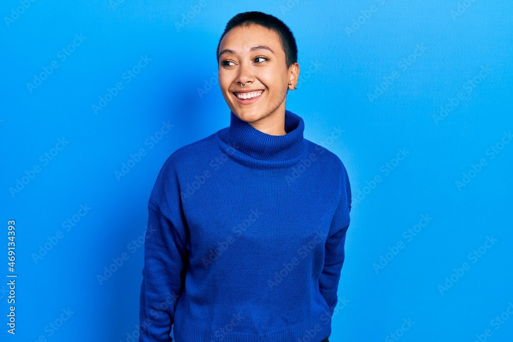 Beautiful hispanic woman with short hair wearing turtleneck sweater looking away to side with smile on face, natural expression. laughing confident. Beautiful hispanic woman with short hair wearing turtleneck sweater looking away to side with smile on face, natural expression. laughing confident.