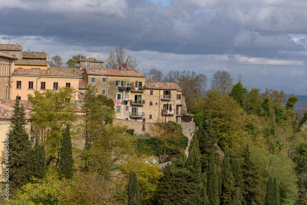 Häuserfassaden zwischen Bäumen und Wolken in Volterra