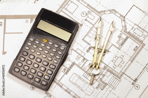 Calculation of the cost of a private country house under construction in the future. The calculator and compasses is on the house plan. 