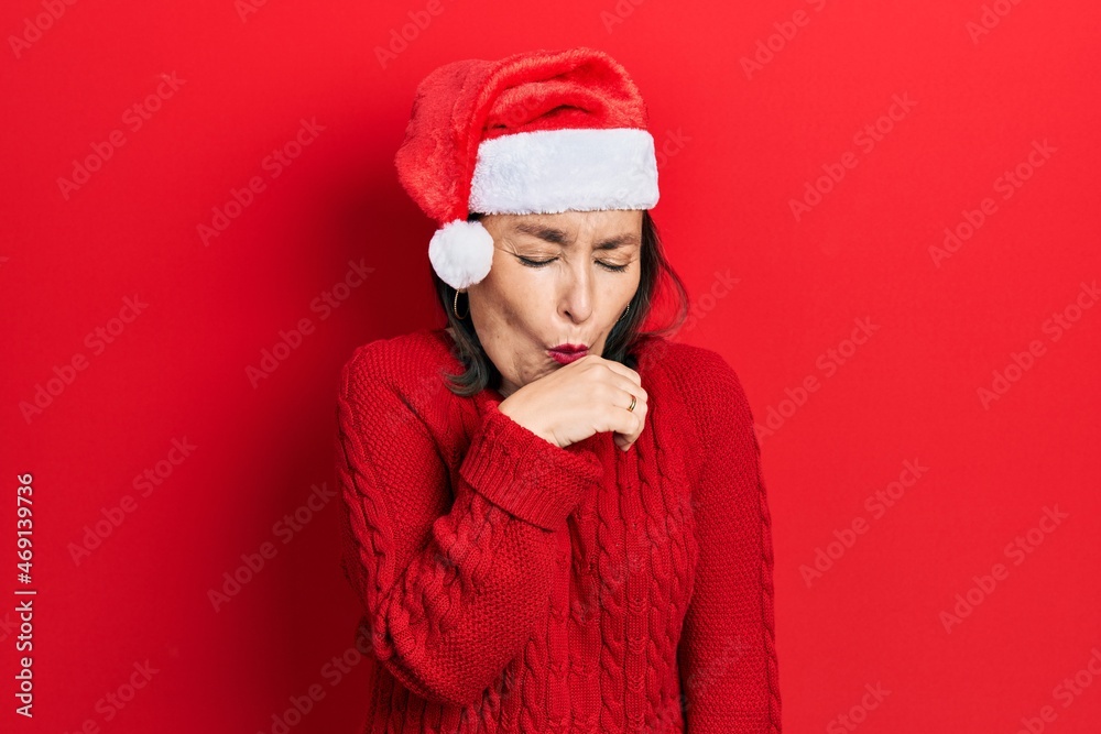 Middle age hispanic woman wearing christmas hat feeling unwell and coughing as symptom for cold or bronchitis. health care concept. Middle age hispanic woman wearing christmas hat feeling unwell and coughing as symptom for cold or bronchitis. health care concept.