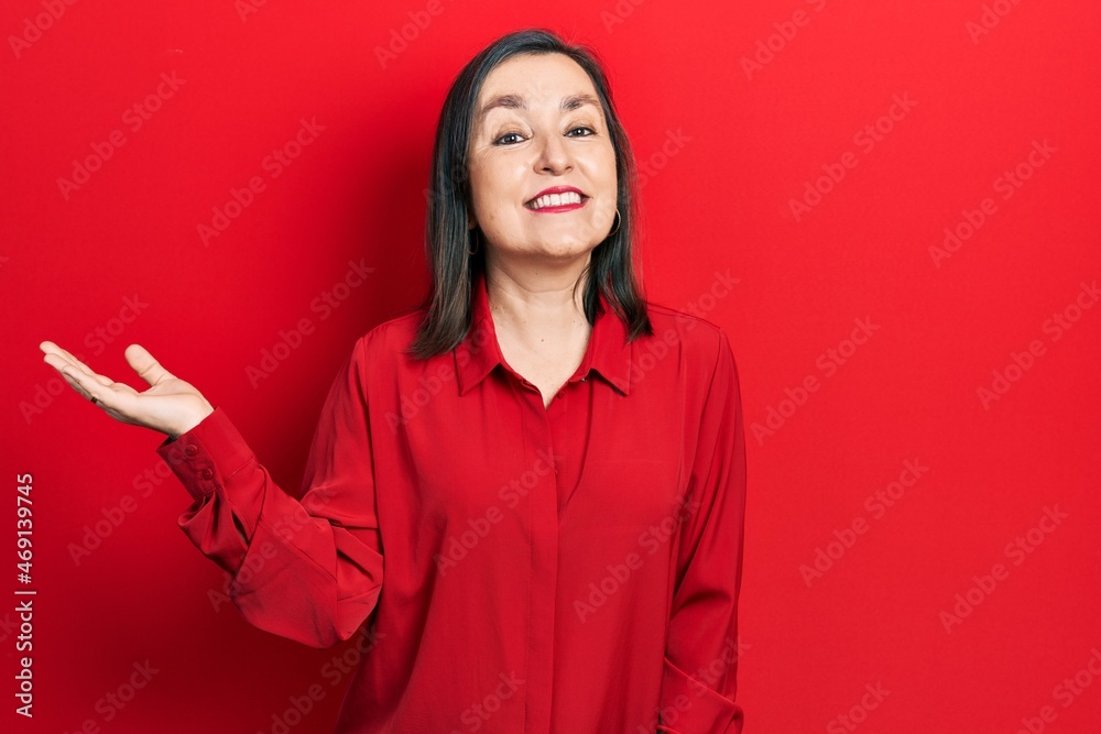 Middle age hispanic woman wearing casual clothes smiling cheerful presenting and pointing with palm of hand looking at the camera. Middle age hispanic woman wearing casual clothes smiling cheerful presenting and pointing with palm of hand looking at the camera.