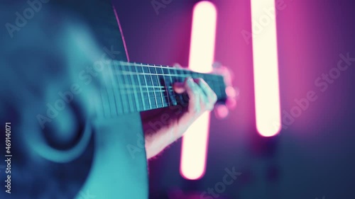 Musician playing acoustic dreadnought guitar with atmospheric purple LED lighting photo