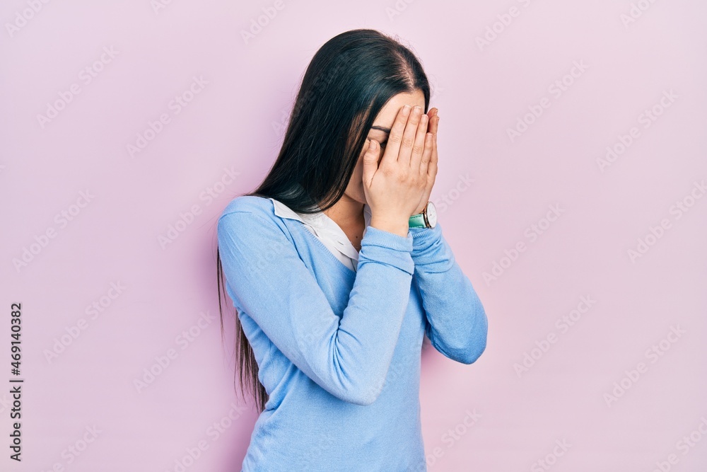 Beautiful woman with blue eyes standing over pink background with sad expression covering face with hands while crying. depression concept. Beautiful woman with blue eyes standing over pink background with sad expression covering face with hands while crying. depression concept.
