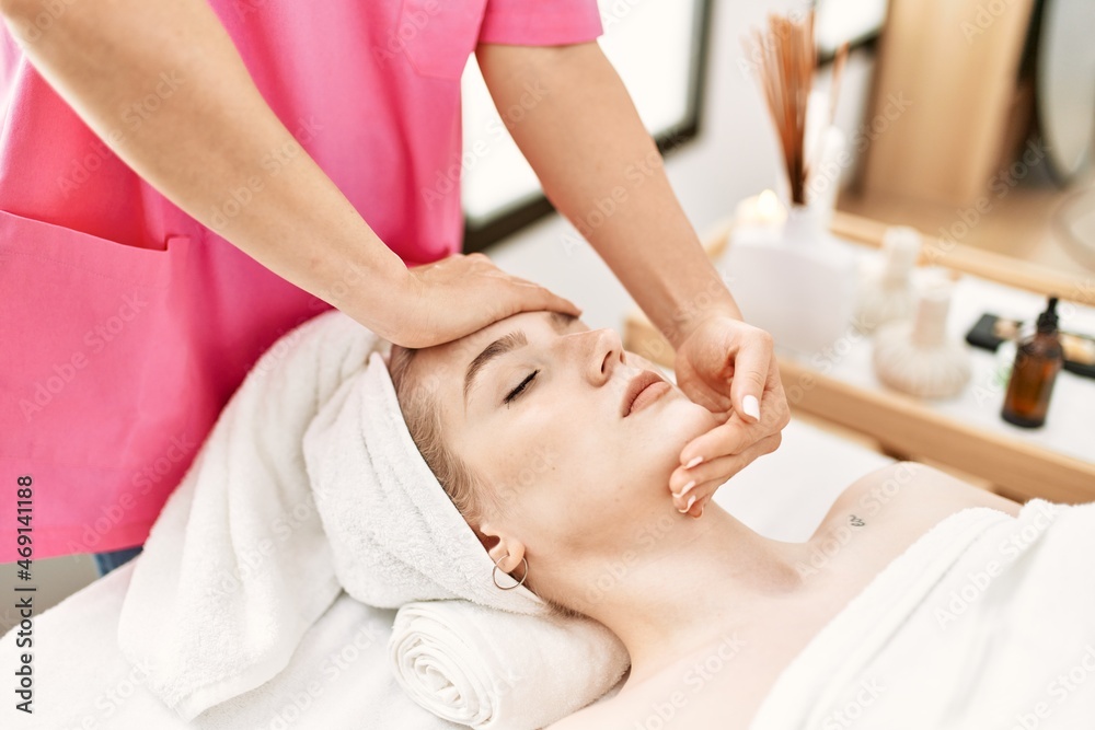 Young caucasian woman relaxed reciving face massage at beauty center.