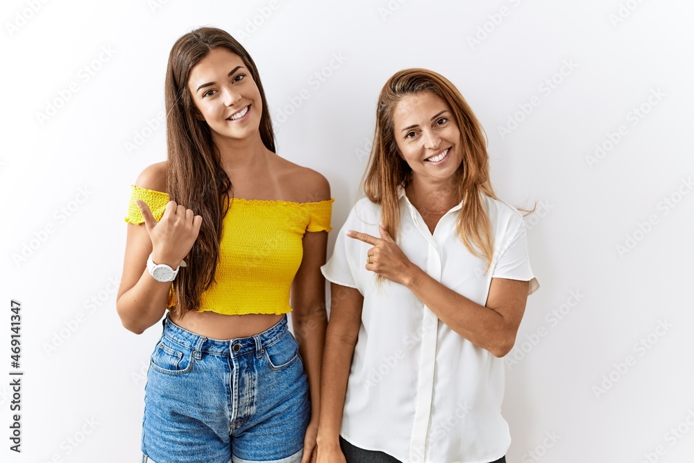 Mother and daughter together standing together over isolated background cheerful with a smile on face pointing with hand and finger up to the side with happy and natural expression Mother and daughter together standing together over isolated background cheerful with a smile on face pointing with hand and finger up to the side with happy and natural expression
