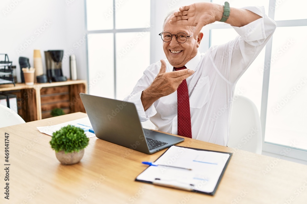 Senior man working at the office using computer laptop smiling making frame with hands and fingers with happy face. creativity and photography concept. Senior man working at the office using computer laptop smiling making frame with hands and fingers with happy face. creativity and photography concept.