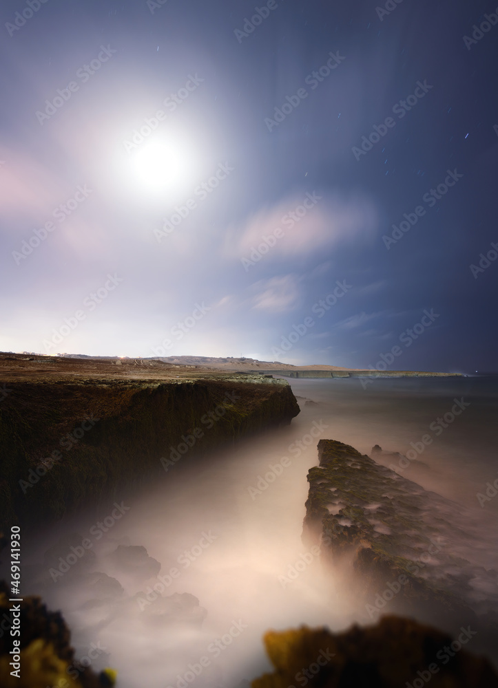 long exposure shot from the beach of Chabahar at night with starry sky located in baluchistan, iran. waves in a Starry night sky over oman sea and beach with cliff and rocks.